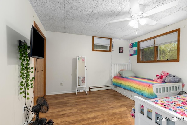 604/606 N New Dexter St, Ionia, MI 48846 - bedroom featuring a baseboard radiator, light wood-style floors, a paneled ceiling, and ceiling fan
