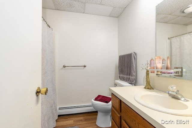 604/606 N New Dexter St, Ionia, MI 48846 - bathroom with a baseboard radiator, a paneled ceiling, toilet, vanity, and wood finished floors