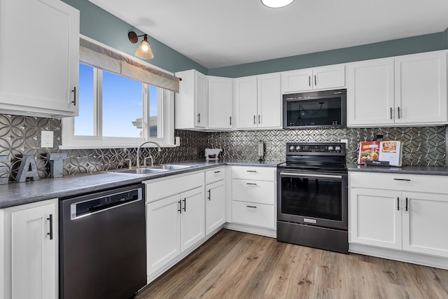 4380 W Chicago Rd, Jonesville, MI 49250 - kitchen with appliances with stainless steel finishes, a sink, dark countertops, white cabinets, and decorative backsplash