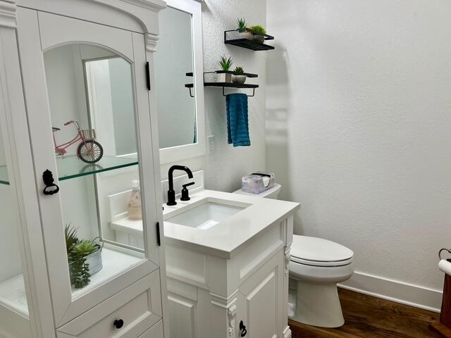 2985 Middle Lake Rd, Twin Lake, MI 49457 - bathroom with vanity, wood finished floors, toilet, baseboards, and a textured wall