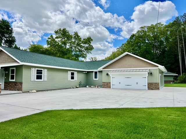 2985 Middle Lake Rd, Twin Lake, MI 49457 - view of front of house featuring stone siding, concrete driveway, a garage, and a front lawn