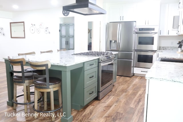 2985 Middle Lake Rd, Twin Lake, MI 49457 - kitchen featuring stainless steel appliances, white cabinetry, exhaust hood, a sink, and a kitchen bar