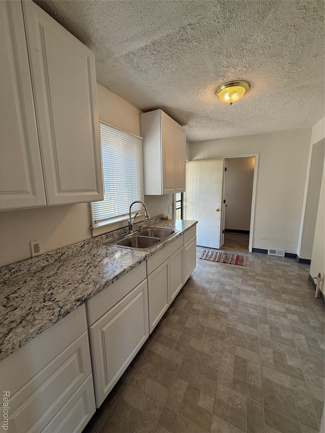 1226 E Princeton Ave, Flint, MI 48505 - kitchen featuring white cabinets, light stone counters, and a textured ceiling