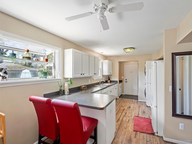 23091 Berdeno Ave, Hazel Park, MI 48030 - kitchen with a sink, freestanding refrigerator, dark countertops, white cabinetry, and ceiling fan