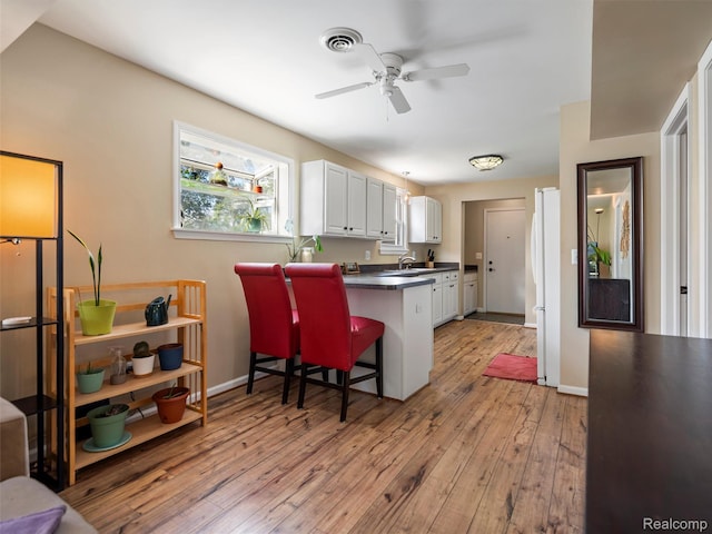23091 Berdeno Ave, Hazel Park, MI 48030 - kitchen featuring dark countertops, light wood-style floors, a peninsula, a ceiling fan, and white cabinets