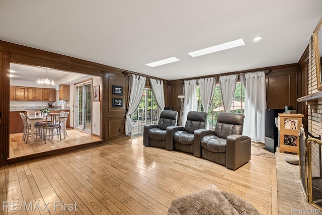 2983 Woodcreek Way, Bloomfield Hills, MI 48304 - living area featuring light wood-style flooring, a chandelier, a skylight, and a brick fireplace