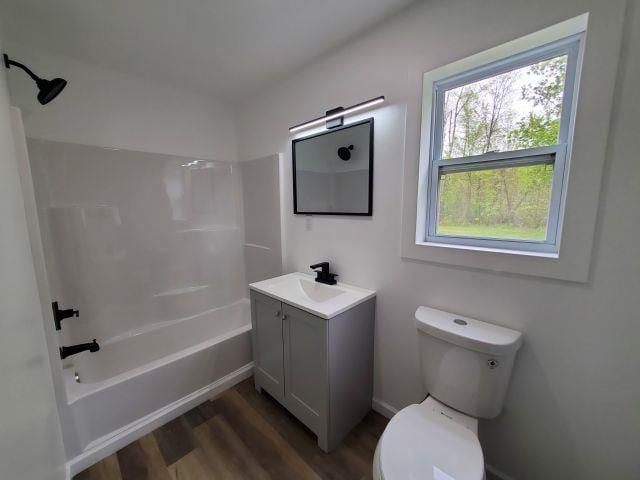 2153 Flowage Lake Rd, West Branch, MI 48661 - bathroom with toilet, vanity, wood finished floors, and washtub / shower combination