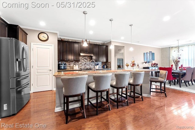 23893 Manistee Ln, Flat Rock, MI 48134 - kitchen with stainless steel refrigerator with ice dispenser, crown molding, dark brown cabinetry, backsplash, and a breakfast bar