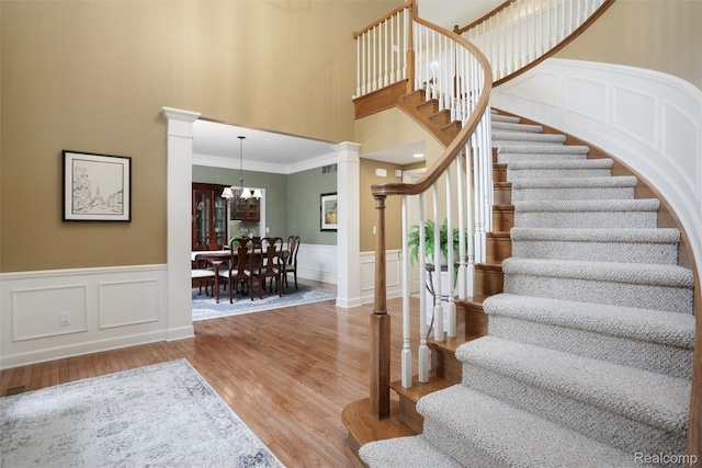 5687 Stonehaven Blvd, Rochester, MI 48306 - stairway with ornate columns, wood finished floors, a chandelier, ornamental molding, and a towering ceiling