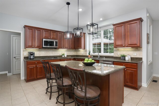 5687 Stonehaven Blvd, Rochester, MI 48306 - kitchen with appliances with stainless steel finishes, a sink, decorative backsplash, light tile patterned floors, and decorative light fixtures