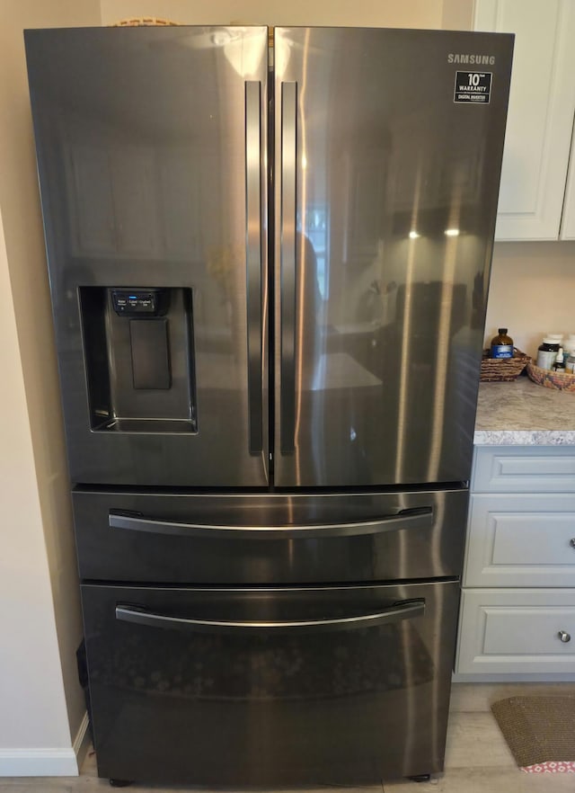 25893 Clark St, Novi, MI 48375 - kitchen view of stainless steel refrigerator with ice dispenser, white cabinetry, wood finished floors, and baseboards