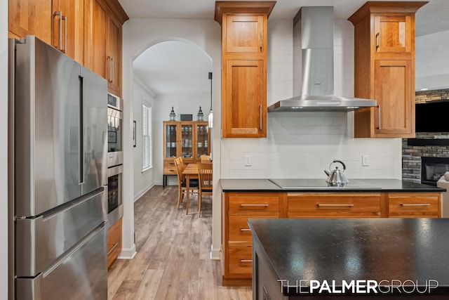 7149 Armadale Ct NE, Belmont, MI 49306 - kitchen with stainless steel appliances, wall chimney range hood, dark countertops, and arched walkways