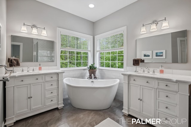 7149 Armadale Ct NE, Belmont, MI 49306 - full bath featuring two vanities, a soaking tub, tile walls, and a wainscoted wall