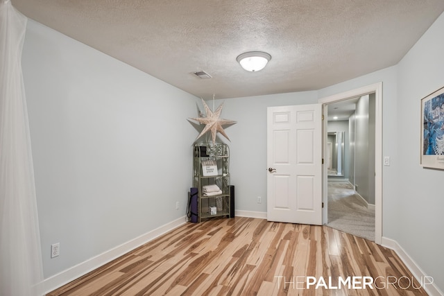 7149 Armadale Ct NE, Belmont, MI 49306 - unfurnished bedroom featuring light wood-style floors, a textured ceiling, and baseboards