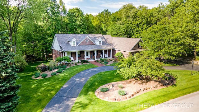 7149 Armadale Ct NE, Belmont, MI 49306 - cape cod home with covered porch, brick siding, a front lawn, and a view of trees