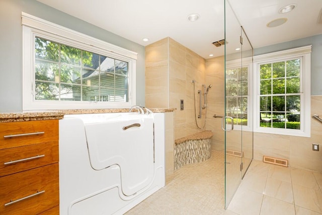 4936 Ravine Ct, Ann Arbor, MI 48105 - bathroom featuring tiled shower, plenty of natural light, a bath, tile patterned flooring, and recessed lighting