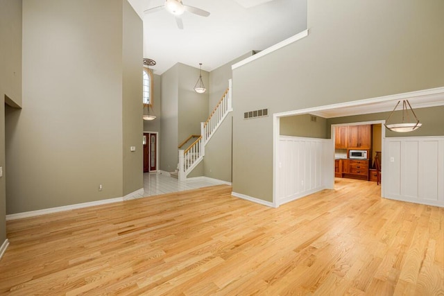 4936 Ravine Ct, Ann Arbor, MI 48105 - unfurnished living room featuring a towering ceiling, stairway, a ceiling fan, light wood finished floors, and baseboards