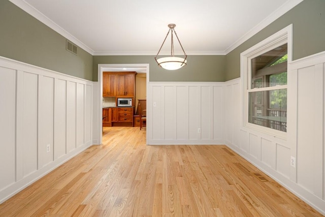 4936 Ravine Ct, Ann Arbor, MI 48105 - unfurnished dining area featuring a decorative wall, light wood-type flooring, crown molding, and wainscoting