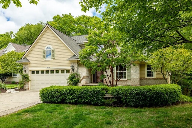4936 Ravine Ct, Ann Arbor, MI 48105 - view of front of home with an attached garage, concrete driveway, brick siding, a front yard, and a shingled roof