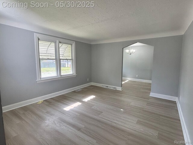 11005 Dodge Ave, Warren, MI 48089 - empty room featuring a chandelier, a textured ceiling, wood finished floors, and baseboards