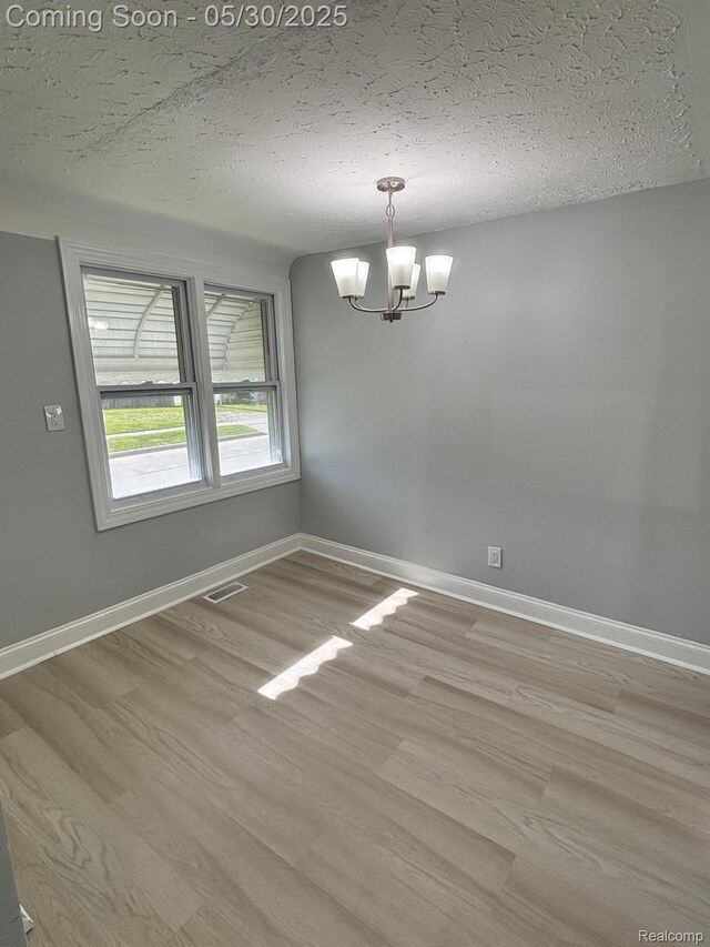 11005 Dodge Ave, Warren, MI 48089 - empty room with a chandelier, light wood-style floors, a textured ceiling, and baseboards