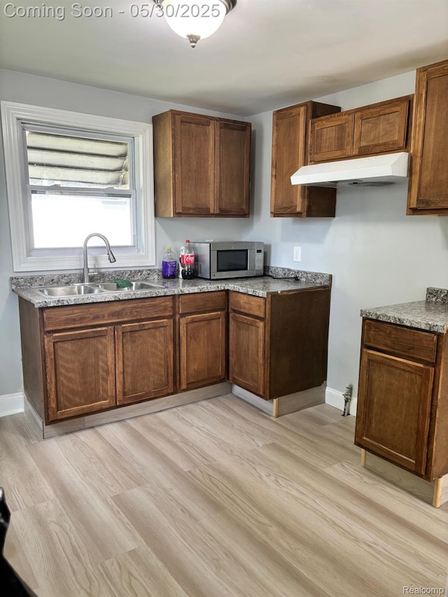 11005 Dodge Ave, Warren, MI 48089 - kitchen featuring stainless steel microwave, a sink, under cabinet range hood, and light wood-style floors