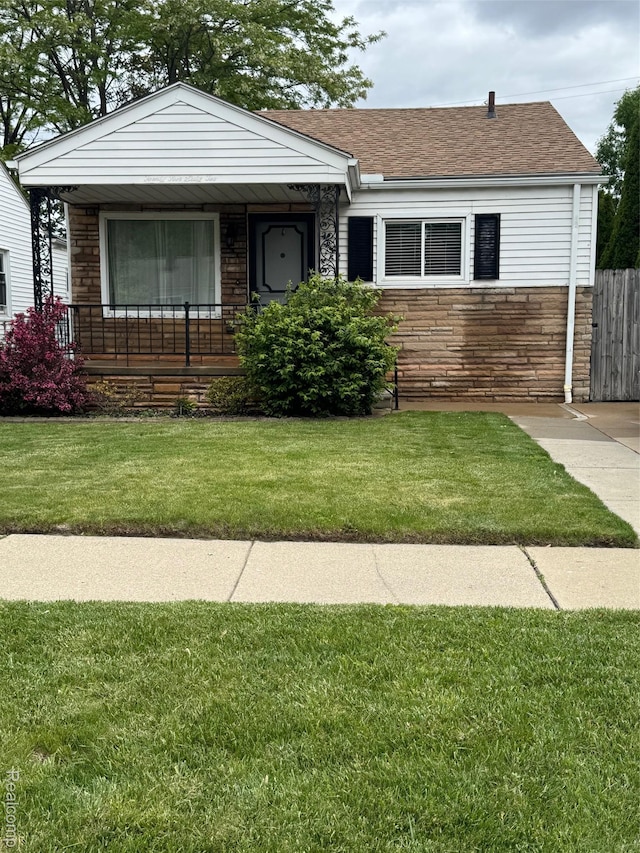2562 Downing St, Melvindale, MI 48122 - view of front facade with stone siding, a front lawn, roof with shingles, and a porch