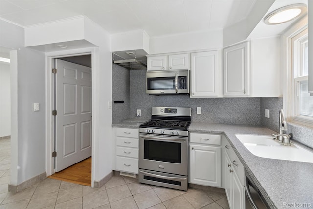 2562 Downing St, Melvindale, MI 48122 - kitchen with stainless steel appliances, light tile patterned flooring, crown molding, white cabinetry, and light countertops