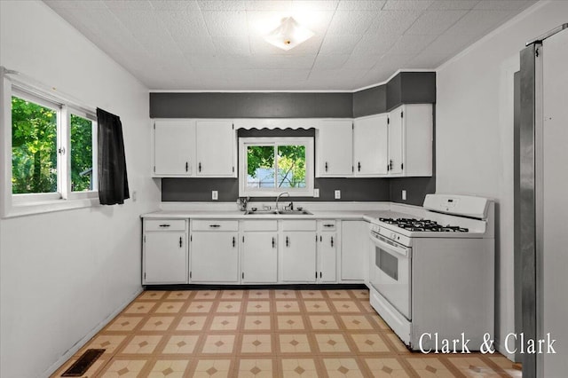 902 Turner Ave, Muskegon, MI 49442 - kitchen with white gas range oven, a sink, light countertops, white cabinetry, and light flooring