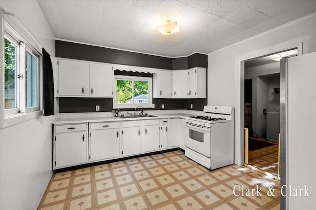902 Turner Ave, Muskegon, MI 49442 - kitchen with white range with gas stovetop, a sink, freestanding refrigerator, light flooring, and light countertops
