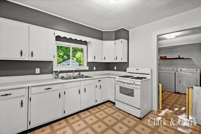 902 Turner Ave, Muskegon, MI 49442 - kitchen with separate washer and dryer, white gas stove, a sink, light flooring, and white cabinetry