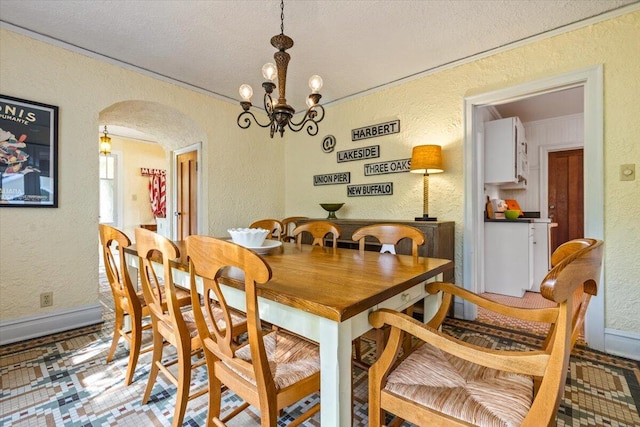 10251 Smith Rd, Union Pier, MI 49129 - dining space with a textured wall, arched walkways, a chandelier, a textured ceiling, and baseboards
