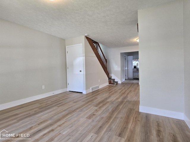 532 Grover St, Owosso, MI 48867 - empty room with stairway, light wood finished floors, baseboards, and a textured ceiling