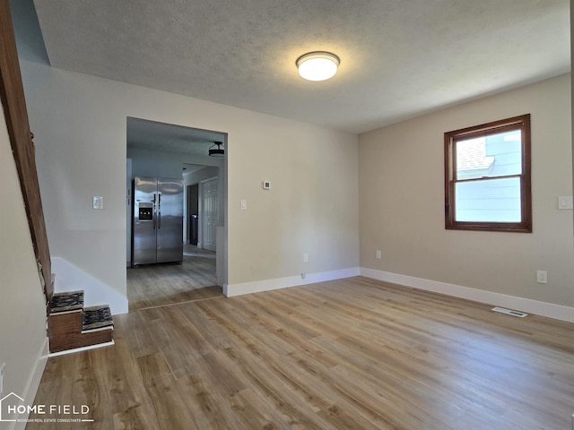 532 Grover St, Owosso, MI 48867 - empty room featuring wood finished floors, baseboards, and a textured ceiling