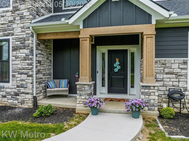 1585 Kriss Crossing Rd, Brighton, MI 48114 - property entrance with stone siding, a porch, board and batten siding, and a shingled roof