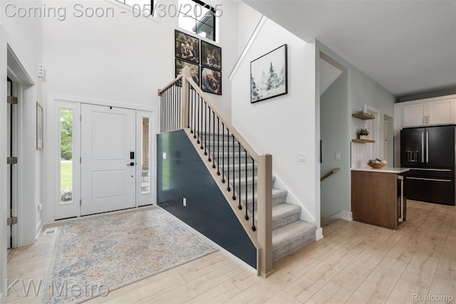 1585 Kriss Crossing Rd, Brighton, MI 48114 - foyer entrance with stairs, light wood-style flooring, a towering ceiling, and baseboards