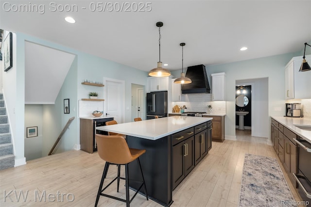 1585 Kriss Crossing Rd, Brighton, MI 48114 - kitchen with black fridge with ice dispenser, premium range hood, tasteful backsplash, light countertops, and recessed lighting