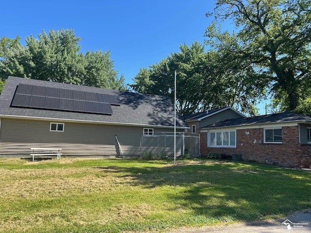 4334 N 4th St, Luna Pier, MI 48157 - rear view of house with solar panels, a lawn, and a shingled roof