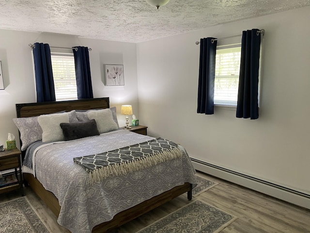 4516 Wah Wah Soo Dr, Gaylord, MI 49735 - bedroom with a baseboard radiator, a textured ceiling, wood finished floors, and multiple windows