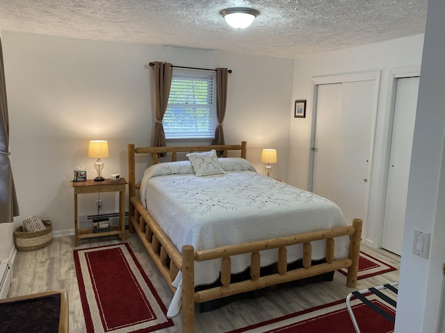 4516 Wah Wah Soo Dr, Gaylord, MI 49735 - bedroom featuring a textured ceiling, wood finished floors, and two closets