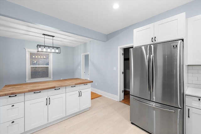 608 Mount Vernon St, Detroit, MI 48202 - kitchen with freestanding refrigerator, butcher block countertops, light wood finished floors, white cabinets, and decorative backsplash