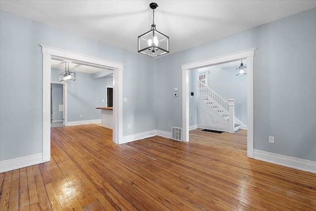 608 Mount Vernon St, Detroit, MI 48202 - unfurnished room with stairway, wood-type flooring, baseboards, and a chandelier