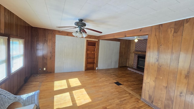 1301 US Highway 10, Scottville, MI 49454 - unfurnished living room with wooden walls, a ceiling fan, wood finished floors, and a fireplace