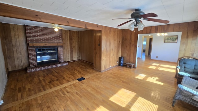 1301 US Highway 10, Scottville, MI 49454 - unfurnished living room with a ceiling fan, wooden walls, wood finished floors, a fireplace, and baseboards