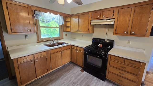 1301 US Highway 10, Scottville, MI 49454 - kitchen with gas stove, under cabinet range hood, a sink, brown cabinets, and a ceiling fan