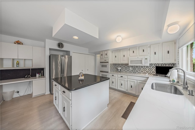 3072 Brewster, West Bloomfield, MI 48322 - kitchen featuring white appliances, a kitchen island, decorative backsplash, light wood finished floors, and white cabinetry