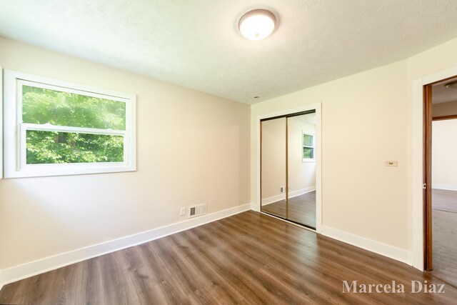 9555 Eastern Ave SE, Byron Center, MI 49315 - unfurnished bedroom featuring dark wood-style floors, a closet, and baseboards