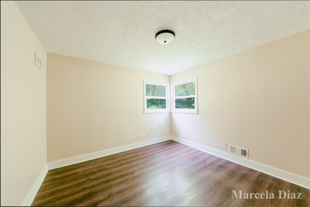 9555 Eastern Ave SE, Byron Center, MI 49315 - empty room featuring dark wood-style flooring, baseboards, and a textured ceiling