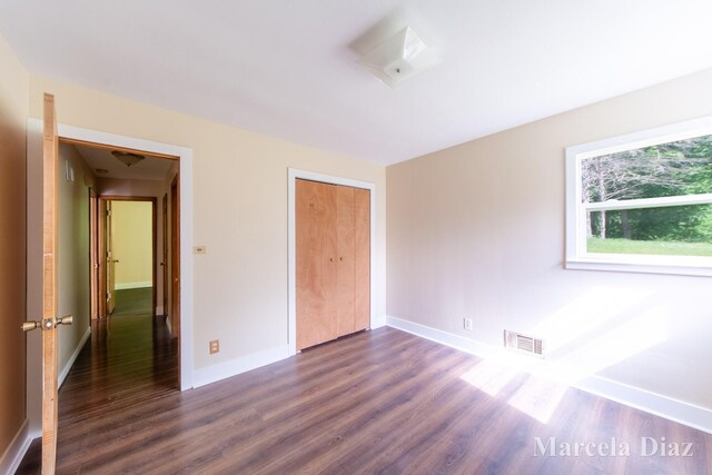 9555 Eastern Ave SE, Byron Center, MI 49315 - unfurnished bedroom featuring dark wood finished floors, baseboards, and a closet