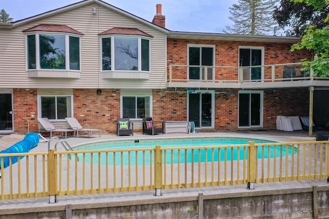 16172 Crest Dr, Linden, MI 48451 - back of property featuring a balcony, brick siding, and an outdoor pool